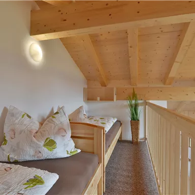 Ein gemütlicher Raum mit Holzdecke und zwei Bänken. Es gibt Kissen und eine Pflanzen dekoriert den Bereich.