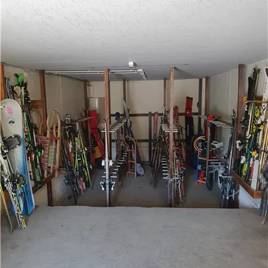 A well-organized ski room with various skis and snowboards. The equipment is neatly stored on shelves.