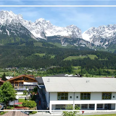 Eine friedliche Landschaft mit schneebedeckten Bergen im Hintergrund. Im Vordergrund befinden sich ein modernes Gebäude und eine Kirche.