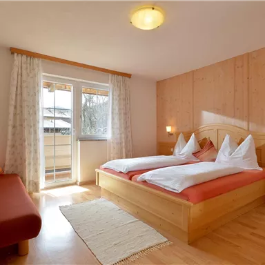 A cozy bedroom with a double bed and a couch. Large windows let in plenty of light and give the room an inviting atmosphere.