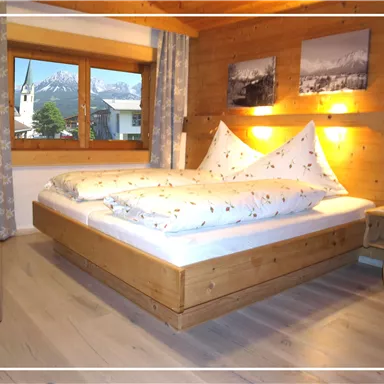 Ein gemütliches Schlafzimmer mit einem Holzbett und einem großen Fenster. Die Wände sind aus Holz, und es gibt Bilder an der Wand.