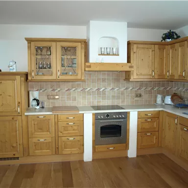 Eine gemütliche Küche mit Holzmöbeln und modernem Design. Es gibt einen Herd und eine große Arbeitsfläche.