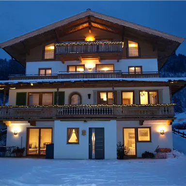 Ein gemütliches Chalet im Schnee mit leuchtenden Fenstern. Die Umgebung ist ruhig und winterlich, ideal für einen entspannenden Rückzugsort.