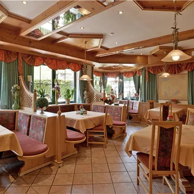 Ein einladendes Restaurant mit Holzdekor und großen Fenstern. Die Tische sind gedeckt und die Atmosphäre ist gemütlich.