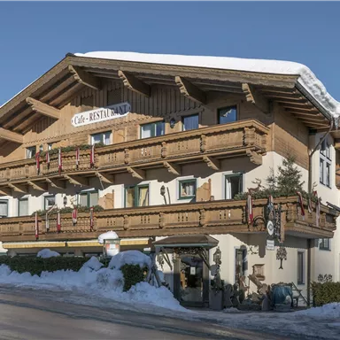 Ein charmantes Berghotel mit traditioneller Architektur und Holzverkleidung. Der umliegende Schnee und die klare Himmel ergänzen die alpine Atmosphäre.