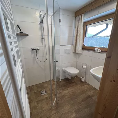 A modern bathroom with shower and bathtub. Bright tiles and wooden details create a cozy atmosphere.