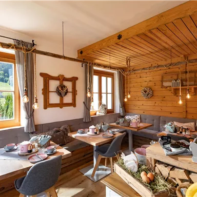 Ein gemütlicher Raum mit Holzwänden und großen Fenstern. Er ist liebevoll eingerichtet und bietet einen Tisch mit Frühstück und Snacks.