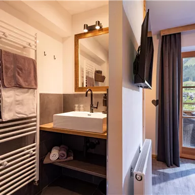 Ein modernes Badezimmer mit einem eleganten Waschbecken und Handtüchern. Durch das Fenster sieht man eine schöne Aussicht auf die Berge.