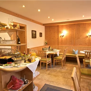 Ein einladendes Restaurant mit holzverkleideten Wänden und Tischen. Auf einem Buffet sind verschiedene Speisen angerichtet.