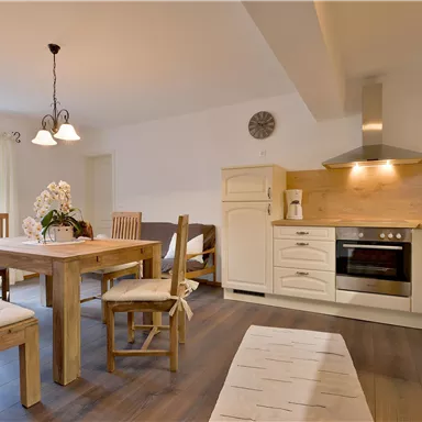 Eine moderne Küche mit einem Essbereich aus Holz. Der Raum ist hell und einladend, mit einer gemütlichen Atmosphäre.