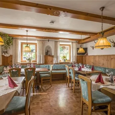 Ein gemütliches Restaurant mit Holzdekor und schönen Tischen. Die Atmosphäre ist einladend und traditionell, mit Warmlicht und dekorativen Elementen.