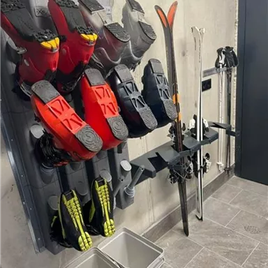 Ski equipment in a modern room. Several pairs of ski boots and skis are neatly lined up.