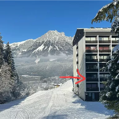 A modern building in a snowy environment with mountains in the background. The winter landscape is picturesque and clear.