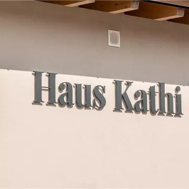 Ein Gebäude mit dem Schriftzug "Haus Kathi" an der Wand. Die Fassade ist hell und modern gestaltet.