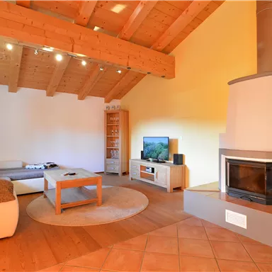 A modern living room with wooden paneling and an open fireplace. There is a cozy sofa, a coffee table, and a television.
