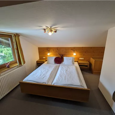 Ein gemütliches Schlafzimmer mit zwei Einzelbetten und Holzverkleidung. Große Fenster sorgen für viel natürliches Licht.