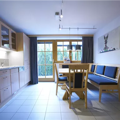A modern kitchen with a bright dining area. Large windows let in plenty of light and provide a view outside.