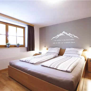 A bright bedroom with a double bed and a cozy atmosphere. Windows looking outside and stylish wall decor.