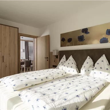 Ein modernes Schlafzimmer mit zwei Betten und einem geräumigen Kleiderschrank. Die Wände sind in hellen Farben gehalten, und ein Kunstwerk ziert die Wand über dem Bett.