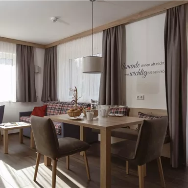 Ein helles, modernes Esszimmer mit einem Holzst Tisch und bequemen Stühlen. Große Fenster sorgen für viel Tageslicht und eine gemütliche Atmosphäre.