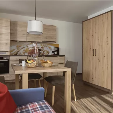 Eine gemütliche Küche mit modernen Möbeln und einem Esstisch. Der Raum ist hell und freundlich gestaltet.