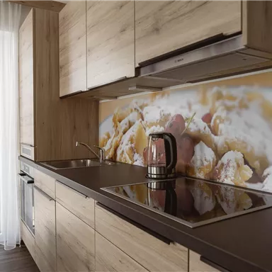 Eine moderne Küche mit Holzregalen und einem Kochfeld. Im Hintergrund ist ein Bild von einem leckeren Gericht zu sehen.