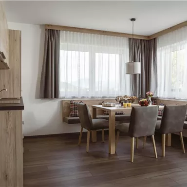 Ein schöner Essbereich mit einem Holztisch und bequemen Stühlen. Große Fenster sorgen für viel Licht und eine einladende Atmosphäre.