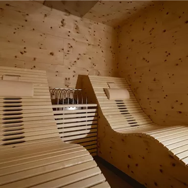 Ein entspannender Raum mit zwei Holzliegestühlen. Die Wände sind aus hellem Holz und schaffen eine ruhige Atmosphäre.