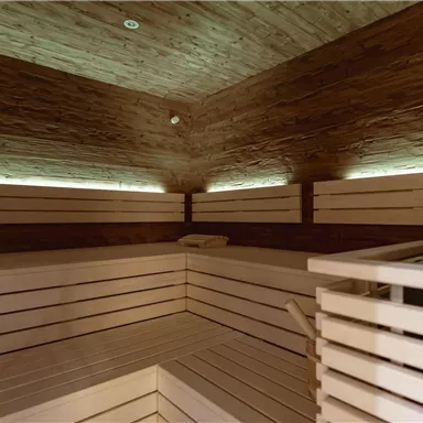 Eine moderne Sauna mit hellen Holzverkleidungen und sanfter Beleuchtung. Der Raum bietet Platz zum Entspannen und Wohlfühlen.