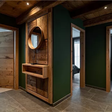 Ein moderner Flur mit Holzvertäfelungen und grünen Wänden. Der Raum hat eine einladende Atmosphäre und zeigt zwei offene Türen zu weiteren Zimmern.