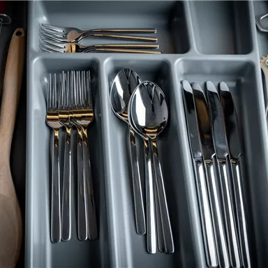 Ein Besteckkasten mit verschiedenen Besteckteilen. Darin befinden sich Löffel, Gabeln, Messer und Holzutensilien.
