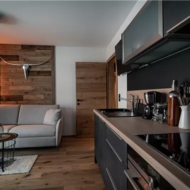 Moderne Küche mit einem gemütlichen Wohnbereich. Heller Holzfußboden und stilvolle Einrichtung schaffen eine einladende Atmosphäre.