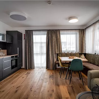 Eine moderne Küchen- und Wohnsituation mit Holzfußboden. Das Zimmer ist hell und gemütlich eingerichtet, mit Fenster und Vorhängen.