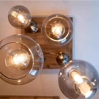 Eine moderne Deckenleuchte mit mehreren Glaskuppeln. Die Lampen strahlen warmes Licht in einem stilvollen Raum.