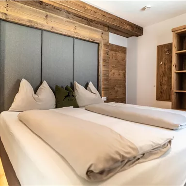Ein gemütliches Schlafzimmer mit einem großen Bett und einer modernen Holzwand. Das Zimmer ist hell und minimalistisch eingerichtet.