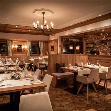 A modern restaurant with elegant tables and chairs. The warm lighting creates an inviting atmosphere.