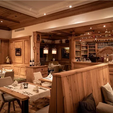 A cozy restaurant with wooden interior and soft lighting. The tables are elegantly set and invite you to linger.