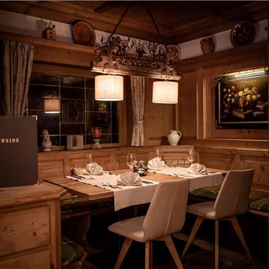 A cozy restaurant with wooden decor and warm lighting. The table is elegantly set and accommodates several guests.