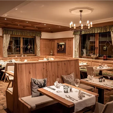 A cozy restaurant with wooden decor and warm lighting. The tables are stylishly set, and there are comfortable seating options.