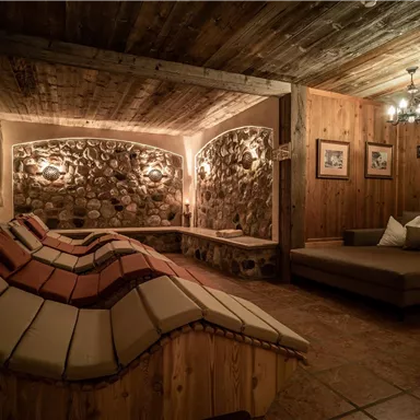 A cozy room with wooden walls and soft lounges. Gentle light and rustic elements create a relaxing atmosphere.