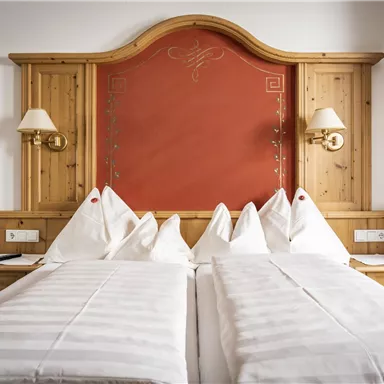 A cozy bedroom with a large bed and white bedding. The wood paneling and the red headboard create an inviting atmosphere.