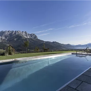 A beautiful outdoor pool with a view of impressive mountains. The clear sky and the tranquil landscape create a relaxed atmosphere.