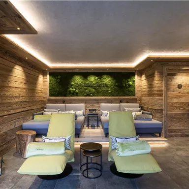 A cozy wellness area with wooden paneling and green plant walls. Comfortable loungers in soft colors invite relaxation.