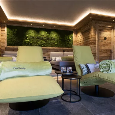 An elegant relaxation room with green loungers and a wooden wall. The atmosphere is modern and soothing, ideal for relaxation.