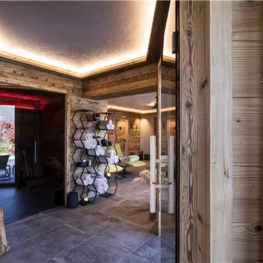 A modern interior with wood paneling and soft lighting. In the background, shelves and a cozy seating area can be seen.