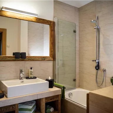 A modern bathroom with a shower and a bathtub. It features wooden details and a bright, inviting atmosphere.