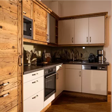 A modern kitchen with wooden fronts and white cabinets. It is well-equipped with appliances and work surfaces.