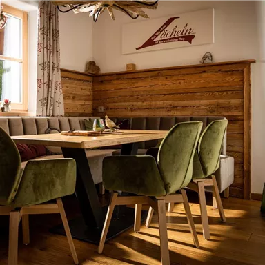 A cozy dining area with a wooden bench and modern chairs. The light gently falls on the wooden paneling, creating a warm atmosphere.