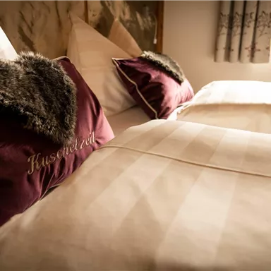 A cozy bedroom with two beds and soft pillows. The pillows are decorated with a pretty heart-shaped design.