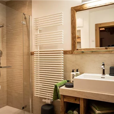 A modern bathroom with a shower and a stylish sink. Wood and tile elements create a cozy atmosphere.